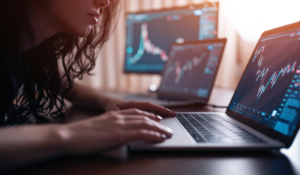 Pessoa analisando gráficos financeiros em laptops