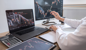 Pessoa analisando gráficos financeiros em desktops