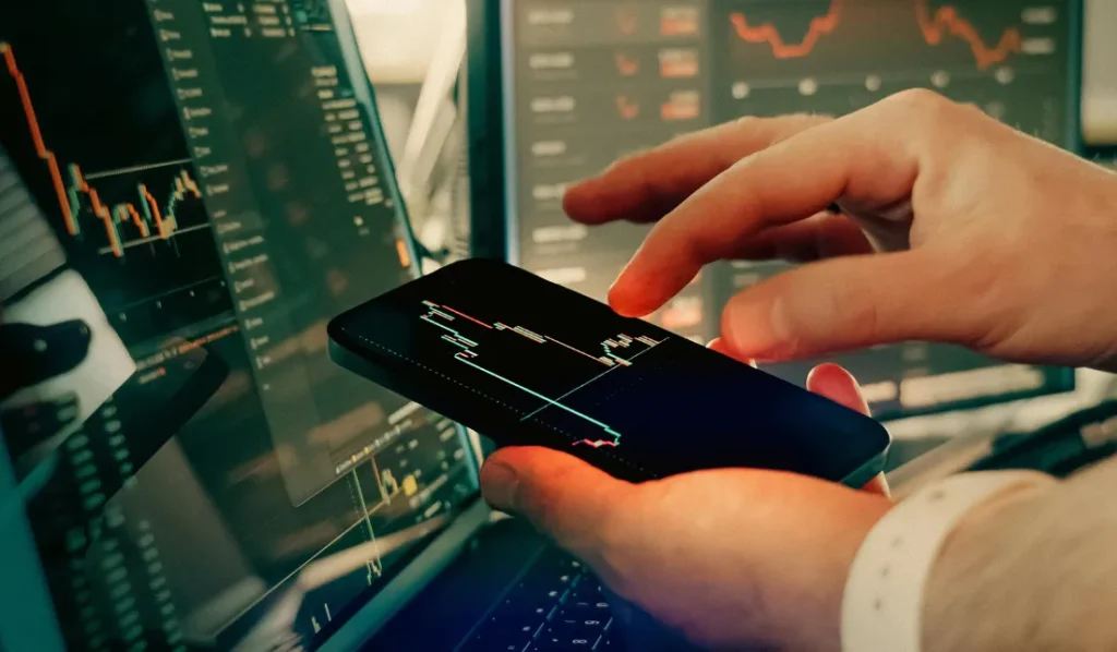 Mão segurando smartphone com gráfico financeiro