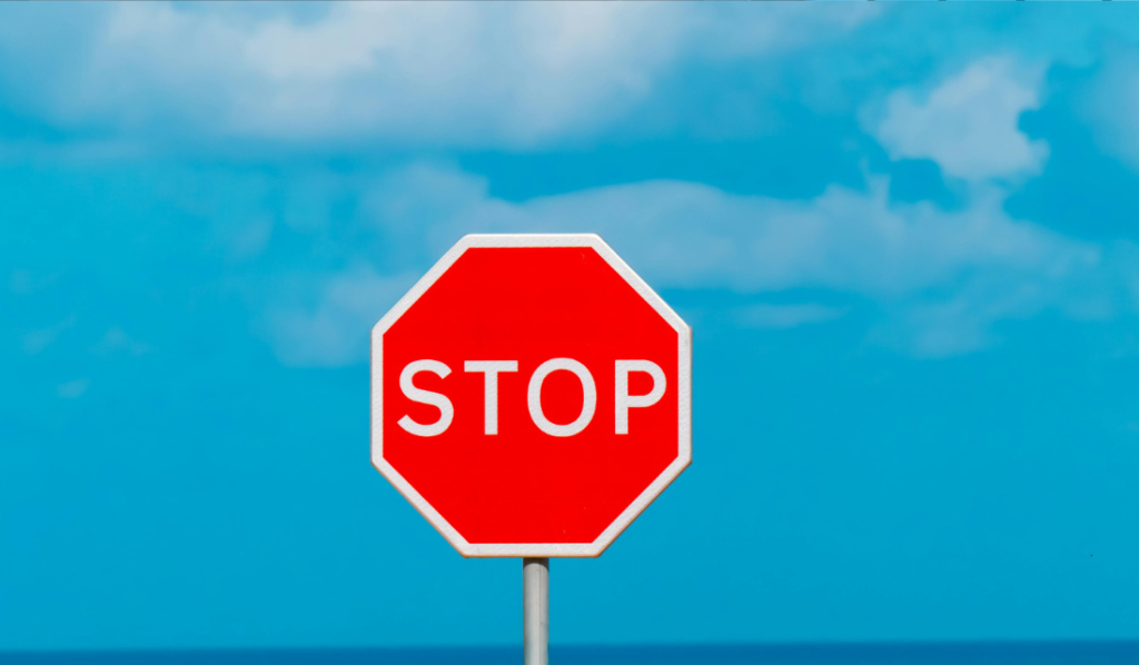 Placa de pare vermelha com fundo azul claro.