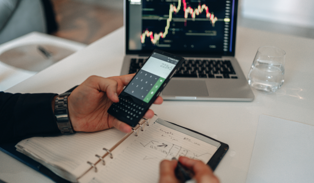 Pessoa usando calculadora e analisando gráficos financeiros