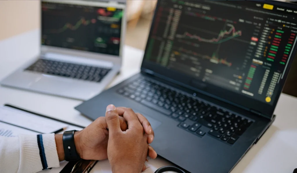 Pessoa analisando gráficos de investimento em laptops